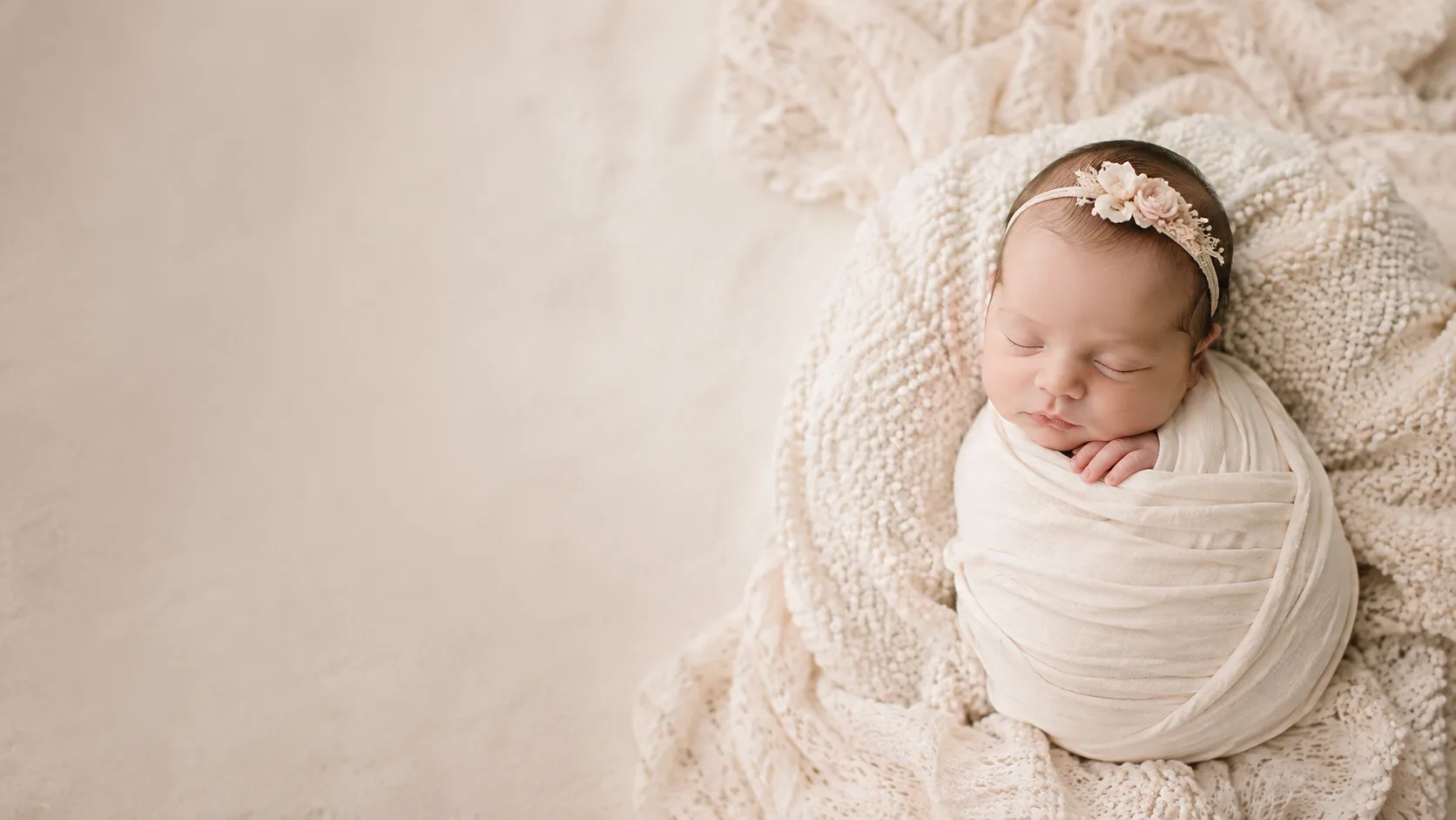 Newborn baby swaddled and sleeping on a cream blanket, photographed by a Raleigh newborn photographer